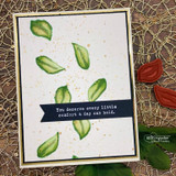 Sample card with green leaf stamps scattered across a gold-splattered cream panel, finished with a navy sentiment strip reading 'You deserve every little comfort a day can hold'.