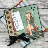 Card with BraeLynn on suitcases layered over patterned paper and a black bow, gray markers alongside.