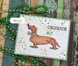 The brown dachshund with a green bow tie on a confetti-print card.
