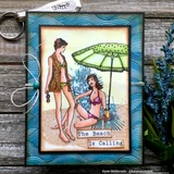 Card with the two beach women coloured in teal and pink under a green umbrella, framed in blue wave-print paper on a metal-ringed album, sentiment "The Beach Is Calling."
