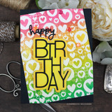 Card with the hearts background embossed white over pink, orange, yellow and green ink, with a yellow birthday word and sequins