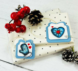 Gift box topped with a blue mitten-ornament tag with red heart accents.