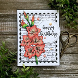 Sample card with the gladiolus colored warm coral over a script background inside a black stitched frame, with a circle die cut stamped 'happy birthday'.
