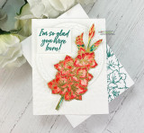 Sample card with the gladiolus colored red and gold, die cut and mounted on a quilted white panel beside a teal sentiment block reading 'I'm so glad you were born'.