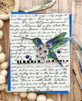 Blue card with a jewel-toned hummingbird and blossoms over the handwritten script panel.