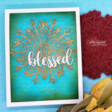 Gold-embossed 'blessed' snowflake on a teal panel beside a rust script-stamped medallion.