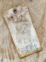 Manila shipping tag stamped with the flower filled paintbrush in warm brown over a distressed background, the Frida Kahlo sentiment inked at the bottom.