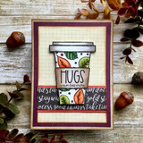 Card with an autumn leaf-print travel coffee mug and a die-cut 'HUGS' over aged text.