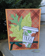 Card with the fall coffee cup and a die-cut oak leaf on a plaid background with 'HUGS.'