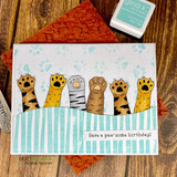 A row of patterned cat paws raised in the air with 'Talk to the paw' and 'You're paw-some,' a punny red rubber cat stamp set shown on a card.