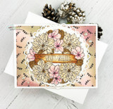 Peach and cream poinsettia wreath on a lacy circle with a sponged pink background and the banner 'Season's Greetings'