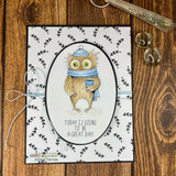 Card with a small leaf-print panel and an oval frame: the owl in a blue hat holding a mug over the great-day sentiment.