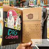 Traveler's journal spread with the girl stamped among flowers and leaves on the left page.