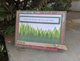 Card sample. A green layered forest panel, 'cherish the moments that warm your heart.'