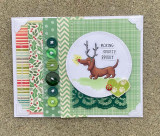 Green holiday-paper card with an antlered dachshund in a circle frame and 'Making spirits bright'