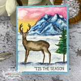 A colored buck standing before snow-capped mountains and a pine tree in a sunset-watercolor scene.