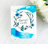 Card with the wreath in blue tones over a watercolor wash, 'happiest wishes.'