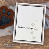 An embossed paw-print card matted with a stitched-rectangle nesting die, 'our hearts go out to you.'