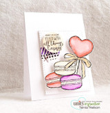 A coral heart lollipop with colorful macarons on a clean white card.