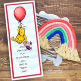 Slimline red-framed card of balloon Pooh beside a rainbow macrame hanger with the adventure quote.