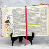 An open Bible on a stand, journaled with the kneeling praying man in the margin.