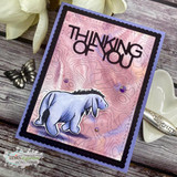 Thinking of You card of Eeyore on a pink topographic stencil with black die-cut letters.