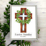 The cross colored in warm wood tones with a green eucalyptus wreath on a lacy-edged white card, reading 'Easter Sunday Blessings.'