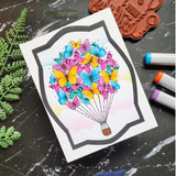 Card with the butterfly balloon in rainbow pinks and yellows over a soft sky.