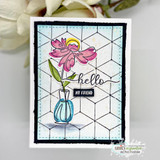 Pale blue geometric background card with a pink daisy in a teal vase, hello in script and a small black my friend label.