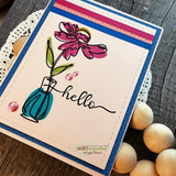 Blush ombre card on a navy base with striped washi at the top, a magenta daisy in a teal vase and a long flowing hello beneath.
