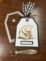 Gift tag with classic Pooh hugging his honey pot, black gingham bow, and 'Missing you greatly'