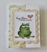 Card with the frog stamped inside a scalloped frame on soft floral paper with a heart accent.