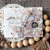 Card with a cluster of shells and a starfish coloured in soft pink and aqua over an embossed white panel with a doily and wood beads, sentiment "Shell Yeah!"