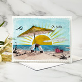 Happy At the Beach card, the seaside umbrella scene colored in soft blues and sandy tans with a sunrise sky.