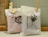 Two glassine gift bags pinned with clothespins, stamped in black with the rose label and the flowering branch label.