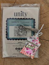 Among the Wildflowers stamp package on a wood round with a pink floral card sample reading "Have a beautiful Birthday" tucked beside it.