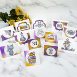 A collection of small Halloween cards — bats, cats, ghosts and a haunted house — stamped over the orange-and-purple script background.