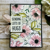Soft pink blooms on the grid background beside 'SENDING LOTS OF HUGS' with a bow