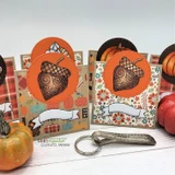 Close-up of small fall cards with orange circles holding the swirly brown acorn above empty banners