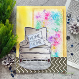 Card with a gray armchair, 'HOME, HOME' pillow over a colorful splatter panel.