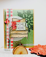 Christmas card with the armchair, a red 'HOME, HOME' pillow and evergreen boughs.