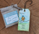 Kraft tag with the bird and 'We fall, we break, we fall, but then we rise, we overcome.'