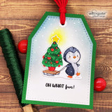 Green scalloped tag with a red tassel: the penguin pulls his glowing star-topped tree over “OH WHAT FUN!”