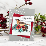 Grey star print card with a red layer and a colored songbird on a branch of red flowers and pinecones, stamped 'merry wishes' and 'FROM OUR HOME TO YOURS'.