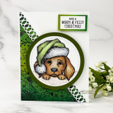 Green-hat puppy in a circle frame on a dark green card, 'have a warm & fuzzy Christmas'.