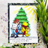 Winnie the Pooh and Christopher Robin read together by a Christmas tree with 'I can already feel the Merry,' a red rubber holiday stamp on a card.