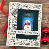 Cream card covered in the sketched pine and berry background, layered with a navy panel and a hand colored snowman in a to-go coffee cup.