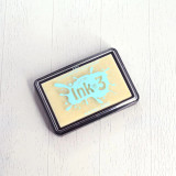 Product photo of the Juicy clear embossing and watermark ink pad from Unity Stamp Co — a black rectangular ink pad case holding a clear, colorless pad with an aqua splash logo reading 'Ink', on a white wood surface.
