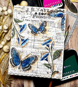 Mixed-media card with blue butterflies and blue blooms over an aged ledger background.