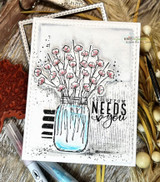 Grungy white card with a blue mason jar of cotton stems and black ink splatter, stamped 'tomorrow NEEDS you.'
